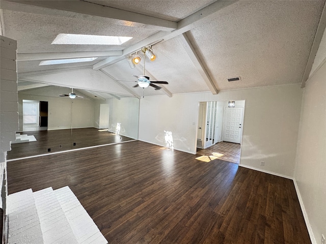 unfurnished living room with a textured ceiling, ceiling fan, lofted ceiling with skylight, and dark wood-type flooring