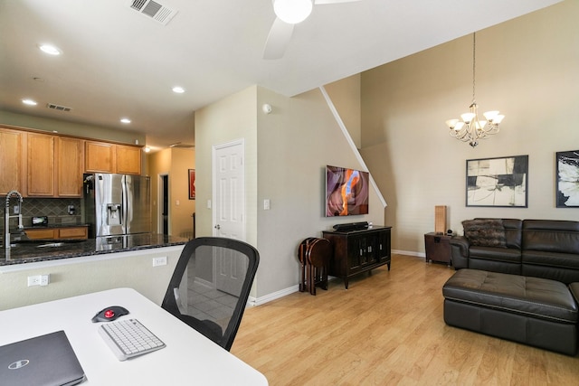 kitchen featuring tasteful backsplash, stainless steel fridge with ice dispenser, hanging light fixtures, dark stone countertops, and light hardwood / wood-style floors