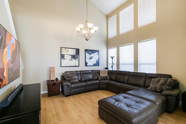 living room featuring a high ceiling, an inviting chandelier, and light hardwood / wood-style floors