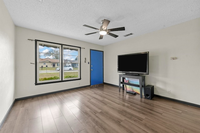 unfurnished living room with a textured ceiling, hardwood / wood-style flooring, and ceiling fan