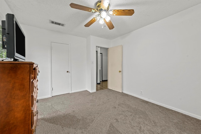 unfurnished bedroom with a textured ceiling, ceiling fan, and dark carpet