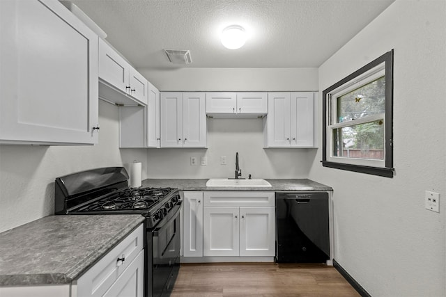 kitchen with white cabinets, sink, black appliances, and hardwood / wood-style floors