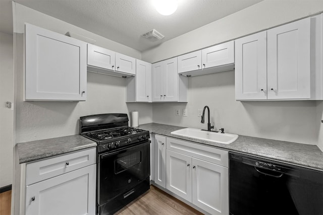 kitchen with black appliances, sink, a textured ceiling, white cabinetry, and light hardwood / wood-style flooring