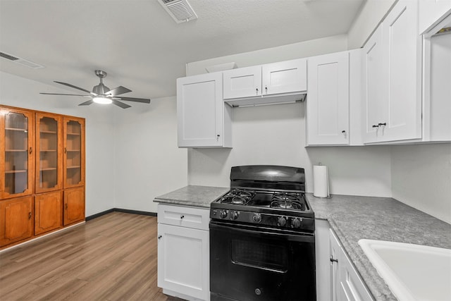 kitchen with a textured ceiling, black range with gas cooktop, light hardwood / wood-style floors, white cabinets, and ceiling fan