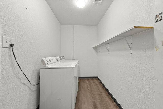 laundry area featuring hardwood / wood-style flooring and washing machine and dryer