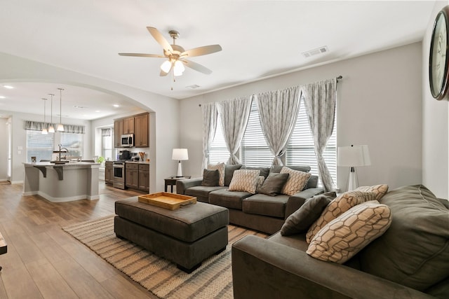 living room with sink, ceiling fan, and light hardwood / wood-style flooring