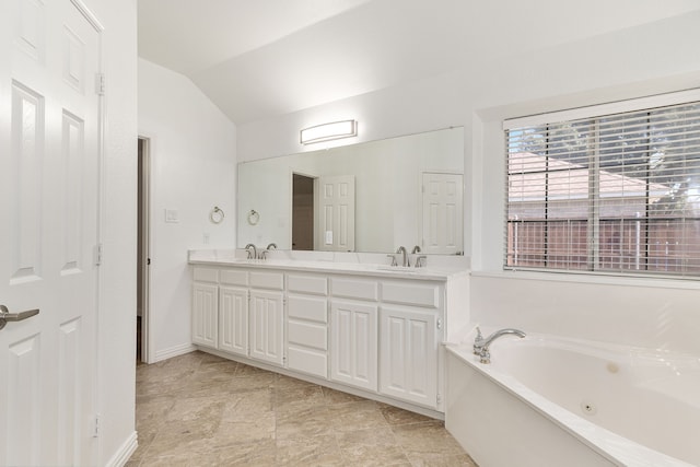 bathroom with lofted ceiling, a tub to relax in, and vanity