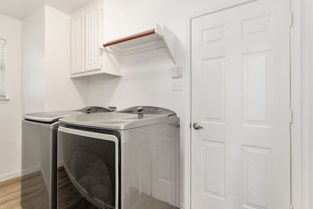 laundry area with cabinets, washer and dryer, and light hardwood / wood-style flooring