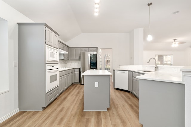 kitchen featuring decorative light fixtures, sink, light hardwood / wood-style floors, white appliances, and a center island