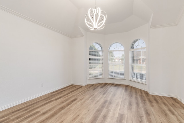 unfurnished room with a notable chandelier, ornamental molding, and light hardwood / wood-style flooring