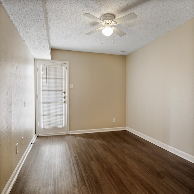 empty room with a textured ceiling, dark hardwood / wood-style flooring, and ceiling fan