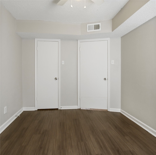 empty room with ceiling fan, a textured ceiling, and dark hardwood / wood-style floors