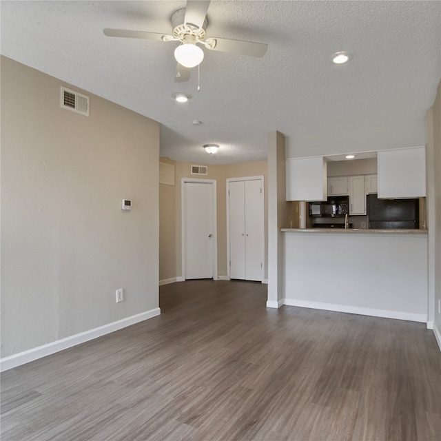 unfurnished living room with a textured ceiling, dark hardwood / wood-style flooring, and ceiling fan