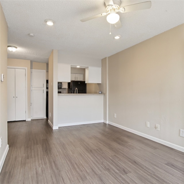 unfurnished living room with ceiling fan, a textured ceiling, and dark hardwood / wood-style flooring