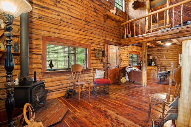 dining room with a high ceiling, a wood stove, hardwood / wood-style flooring, and log walls