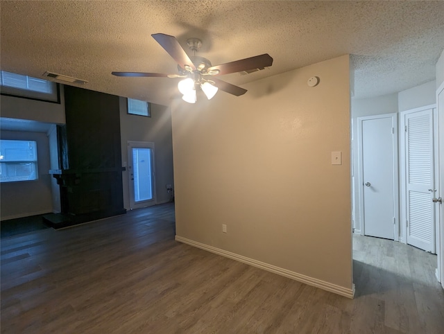 empty room featuring ceiling fan, a textured ceiling, and dark hardwood / wood-style floors