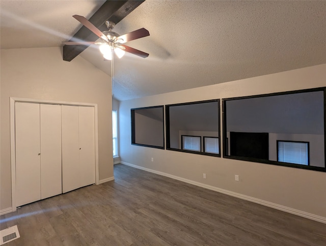 unfurnished bedroom with hardwood / wood-style flooring, ceiling fan, and lofted ceiling with beams