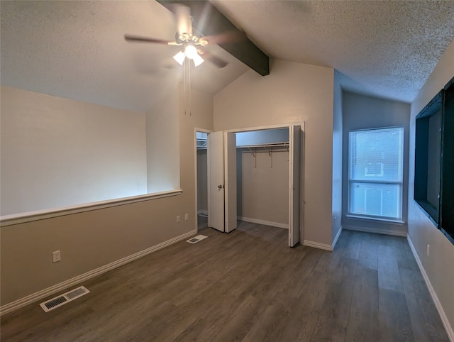 unfurnished bedroom featuring a closet, vaulted ceiling with beams, a textured ceiling, dark hardwood / wood-style flooring, and ceiling fan