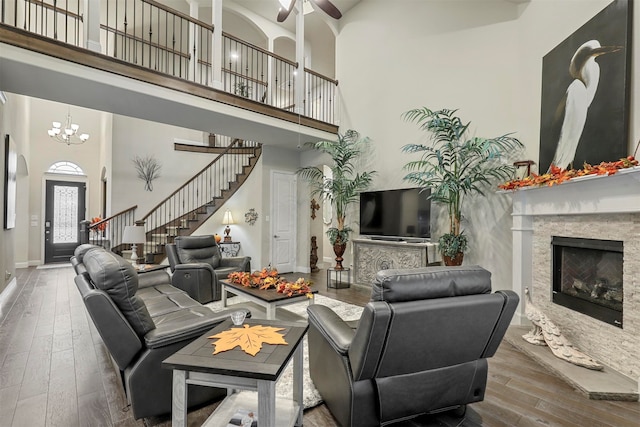 living room with a fireplace, a chandelier, hardwood / wood-style flooring, and a towering ceiling