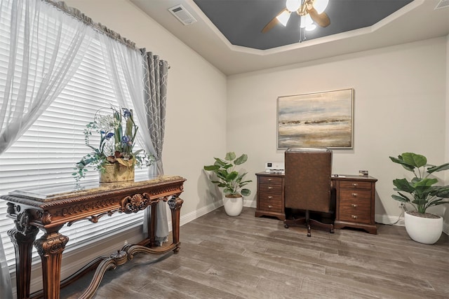 office space featuring hardwood / wood-style floors, ceiling fan, and a raised ceiling