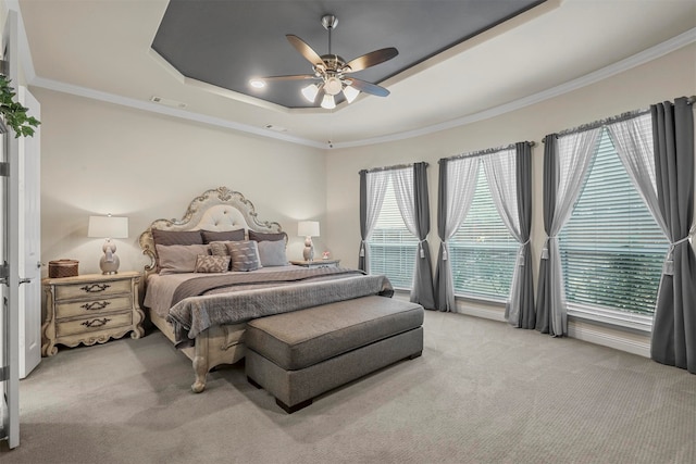 carpeted bedroom with ornamental molding, ceiling fan, multiple windows, and a tray ceiling