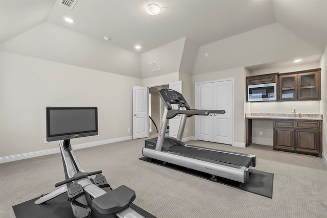 exercise room with light carpet, sink, and vaulted ceiling