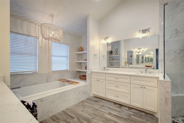 bathroom featuring built in shelves, an inviting chandelier, tiled bath, wood-type flooring, and vanity