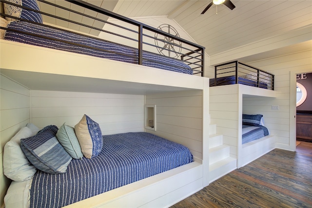 bedroom featuring dark wood-type flooring, high vaulted ceiling, wooden walls, beamed ceiling, and ceiling fan