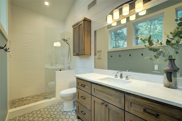 bathroom featuring tiled shower, vanity, and toilet