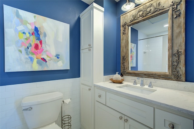 bathroom with a shower, vanity, toilet, and tile walls