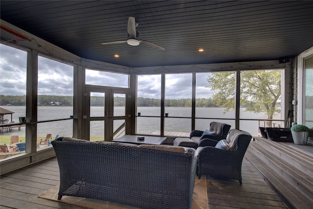 sunroom with ceiling fan, a water view, and a healthy amount of sunlight