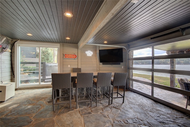 dining space featuring wooden ceiling, beamed ceiling, and wood walls