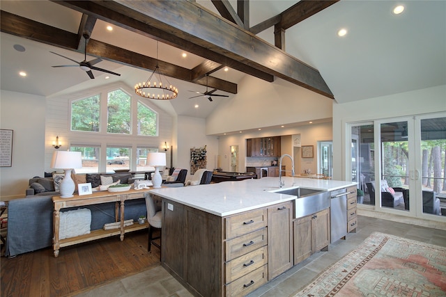 kitchen with beamed ceiling, high vaulted ceiling, sink, and a large island with sink