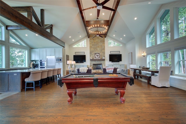 rec room with high vaulted ceiling, dark hardwood / wood-style floors, billiards, a fireplace, and ceiling fan with notable chandelier