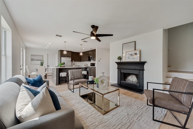 living room featuring sink, ceiling fan, and light hardwood / wood-style flooring