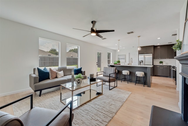 living room featuring light hardwood / wood-style floors, ceiling fan, and sink