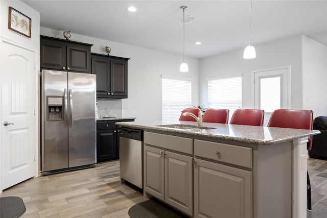 kitchen with appliances with stainless steel finishes, a center island with sink, light hardwood / wood-style floors, and sink