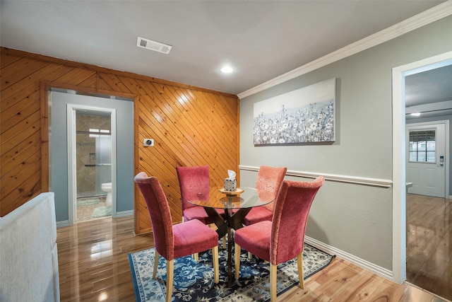 dining space featuring wood walls, dark hardwood / wood-style floors, and crown molding