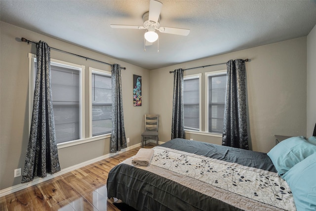 bedroom with multiple windows, hardwood / wood-style floors, a textured ceiling, and ceiling fan