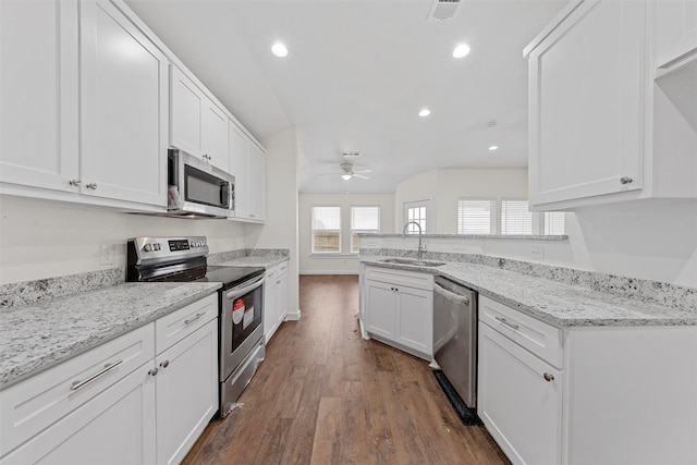 kitchen with sink, dark wood-type flooring, stainless steel appliances, light stone countertops, and white cabinets