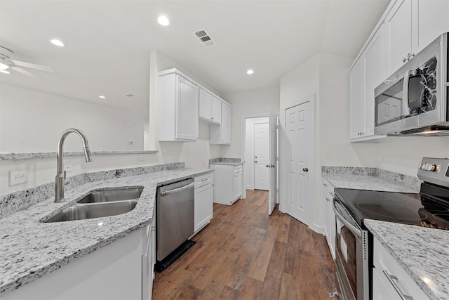 kitchen featuring sink, white cabinetry, stainless steel appliances, dark hardwood / wood-style floors, and light stone counters