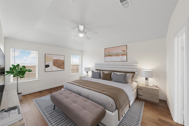 bedroom with ceiling fan, a raised ceiling, and light wood-type flooring