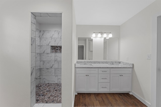 bathroom featuring hardwood / wood-style flooring, vanity, and tiled shower