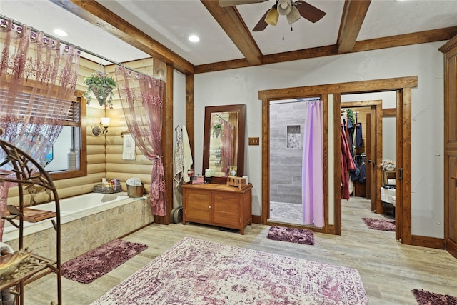 bathroom with beamed ceiling, a relaxing tiled tub, hardwood / wood-style floors, and ceiling fan