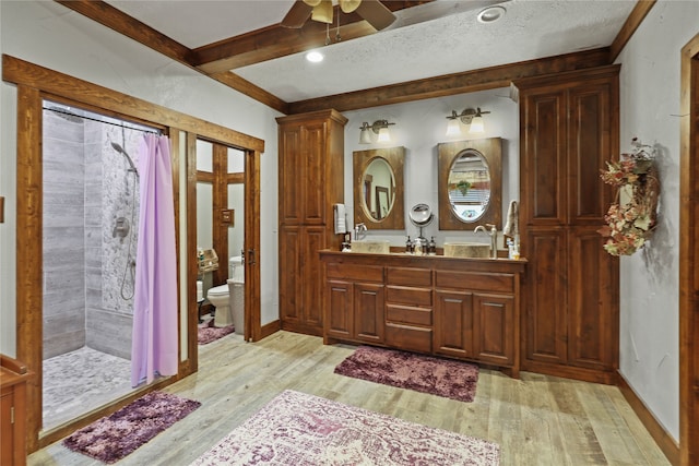 bathroom featuring ceiling fan, curtained shower, wood-type flooring, vanity, and toilet