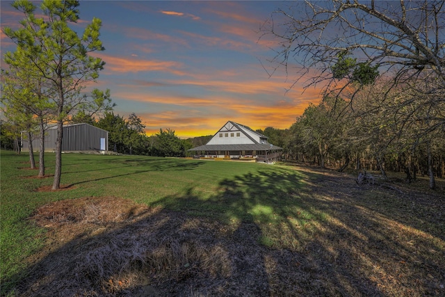 yard at dusk featuring an outdoor structure