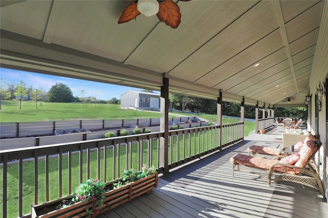 wooden deck featuring a shed, ceiling fan, and a yard