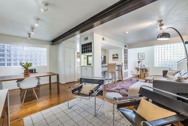 living room with hardwood / wood-style floors, beamed ceiling, and built in shelves