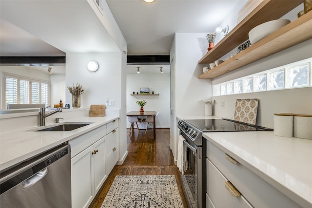 kitchen with light stone counters, stainless steel appliances, sink, white cabinets, and dark wood-type flooring