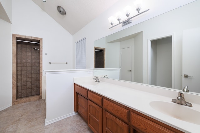 bathroom featuring lofted ceiling, a textured ceiling, a tile shower, and vanity